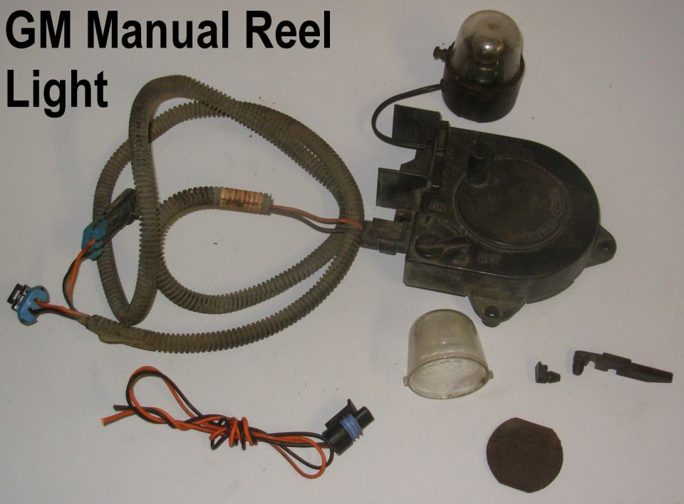 Disassembled GM manual reel light with housing, wiring harness, lens and connectors on white background.