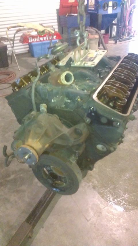 1973 Chevrolet Camaro - An engine block is being lifted by chains in a workshop environment.