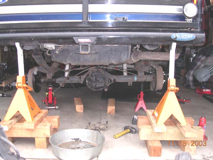 Underside of a truck on jack stands in a garage showing rear axle, driveshaft and exhaust, dated 11-15-2003