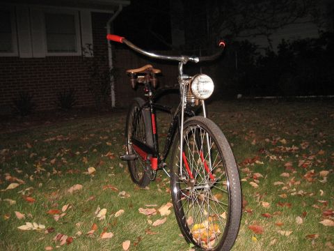 1994 Ford Bronco - A vintage-style bicycle with a prominent headlight sits on a lawn covered in fallen leaves.