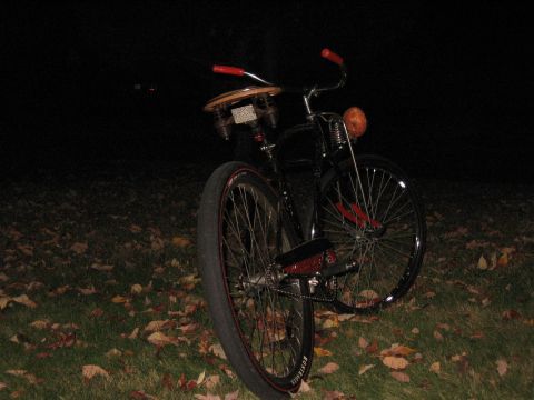 1994 Ford Bronco - A custom bicycle with red handlebars and a wooden seat is parked on grass with fallen leaves.