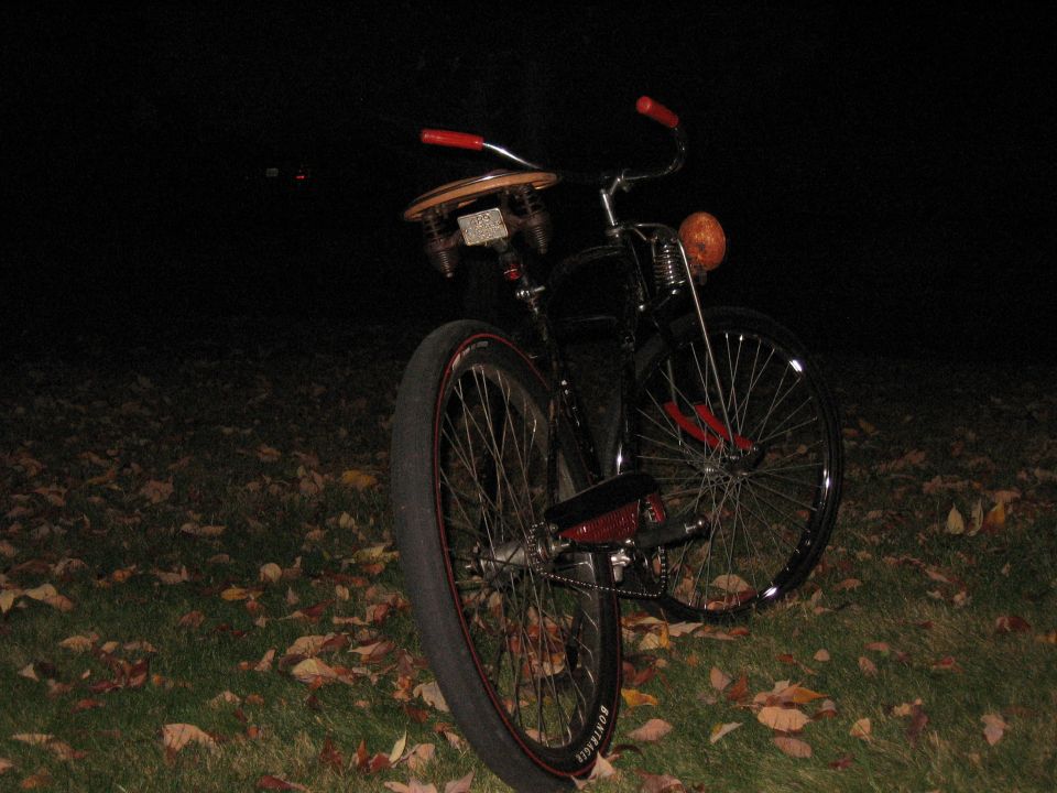 Custom bicycle with red handlebars, wooden seat, and orange headlight