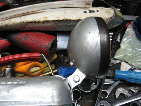 1994 Ford Bronco - A close-up view of a vintage headlight, surrounded by various tools and parts, suggesting a workshop or storage setting.