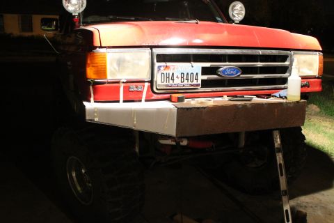 1990 Ford Bronco - A red Ford Bronco's front end is shown with a custom bumper installation in progress.
