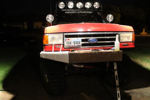 1990 Ford Bronco - Front view of a red 1990 Ford Bronco, a custom bumper and a "Rough Country" light bar overhead.