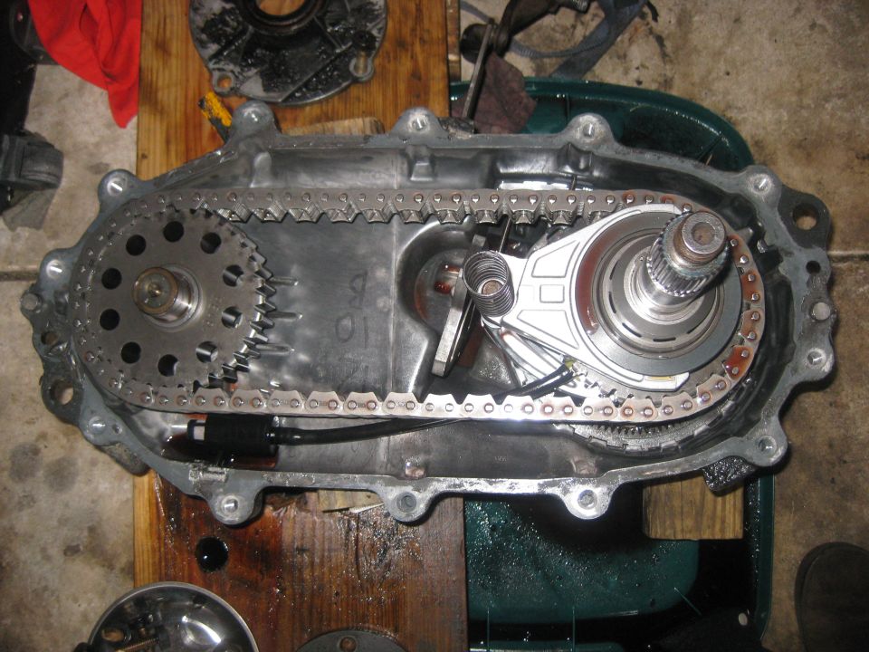 Transfer case disassembled, showing chain, gears, and housing. Some oil is visible