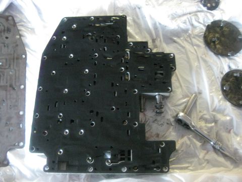 1994 Ford Bronco - A disassembled transmission valve body lies on a plastic sheet with tools and other components.