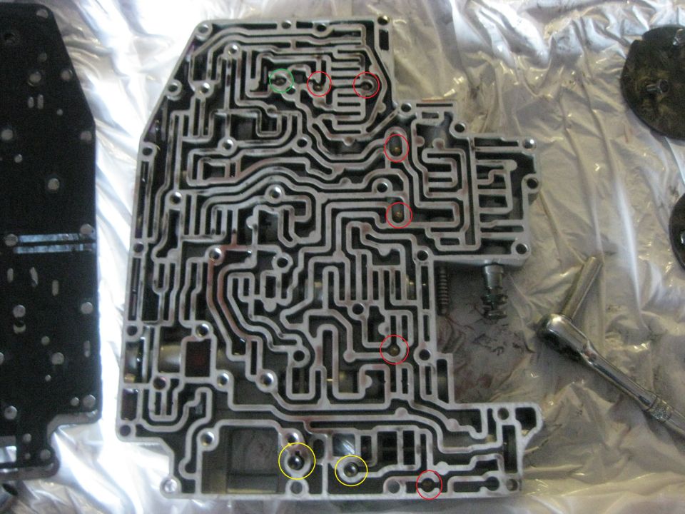 Automatic transmission valve body with intricate channels and ports. A ratchet is visible to the right