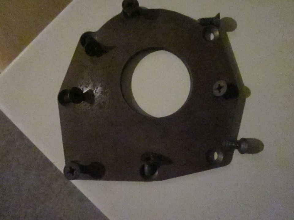 Dark metal oil pump part with central hole and screw holes