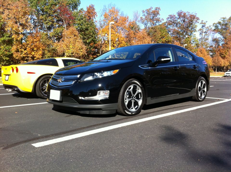 Yellow 2009 Chevrolet Corvette parked next to a black Chevrolet Volt in a parking lot