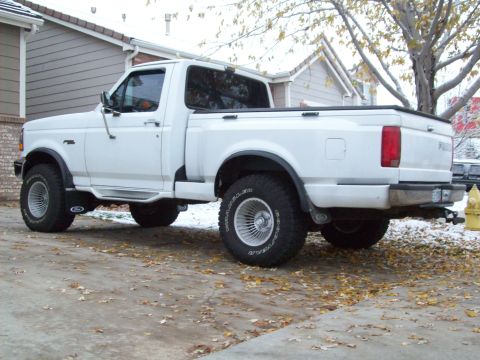1993 Ford F-150 - A white pickup truck is parked on a driveway with fallen leaves and a hint of snow on the ground.