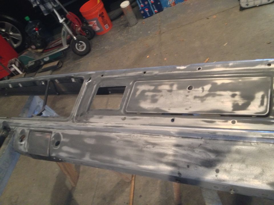Gray metal car dashboard panel with holes and rectangular cutouts, undergoing repair