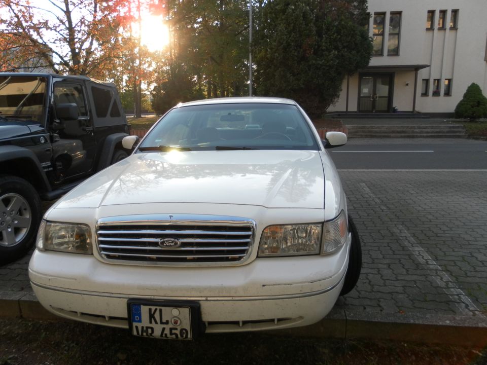 White 1998 Ford Crown Victoria parked in a lot, front view, with a dark Jeep partially visible to the left