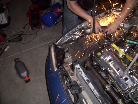 1995 Ford Probe - A person grinds on the engine of a blue car, creating a shower of sparks.