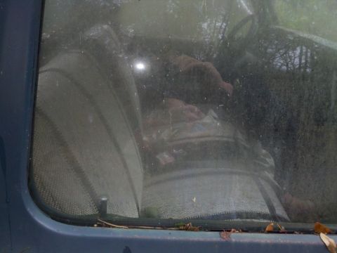 1978 Ford Bronco - The interior of a vehicle is seen through a dirty windshield, showing seats and the steering wheel.
