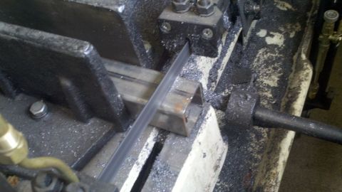 1978 Ford Bronco - A metal cutting band saw is used to cut through square tubing, creating metal shavings.