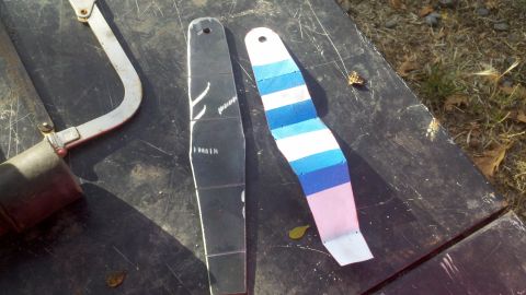 1978 Ford Bronco - A hacksaw and two strips of material are laid out on a dark surface, possibly for a project.