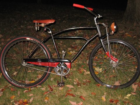 1994 Ford Bronco - A black cruiser bicycle with red accents sits on grass covered in fallen leaves at night.