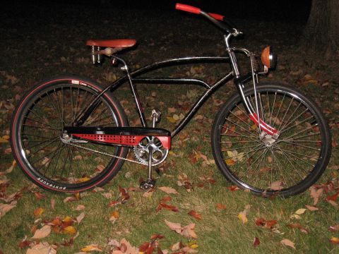 1994 Ford Bronco - A black cruiser bicycle with red accents on the handlebars, seat, and chain guard sits on a grassy lawn covered in fallen leaves.