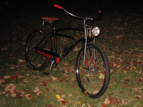 1994 Ford Bronco - A vintage-style bicycle with a black frame and red accents sits on grass covered in fallen leaves.