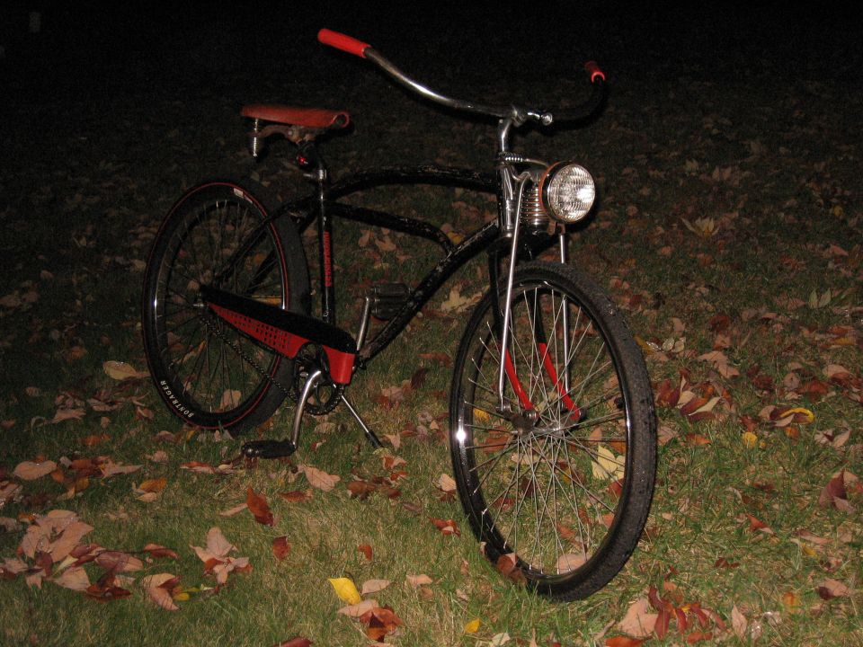 Black cruiser bicycle with red handlebars, seat, and fender accents