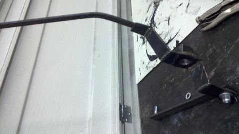 1978 Ford Bronco - A close-up view of a metal bracket and rod assembly, possibly a door mechanism or part of a larger structure.