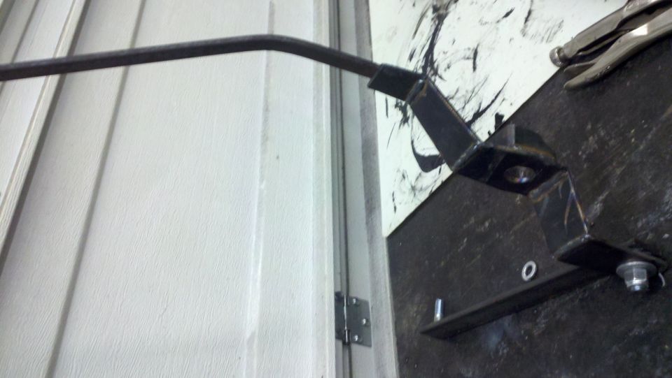 Metal bracket and rod assembly attached to a white door frame