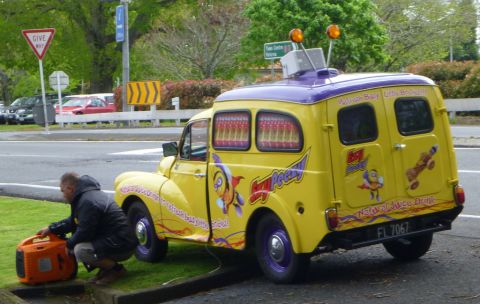 1969 MINI Cooper - A man is setting up a generator next to a brightly colored ice cream van.