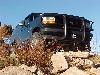 1995 Ford Bronco - This black SUV is navigating a rocky terrain under a clear blue sky.