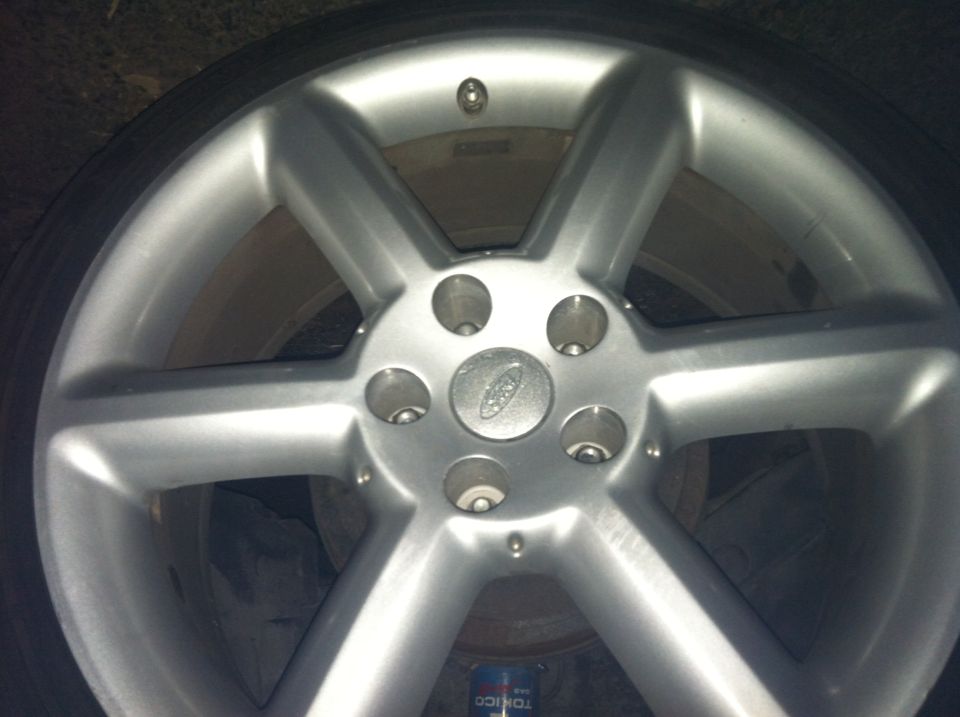 Close-up of a silver five-spoke alloy wheel with a Ford logo in the center