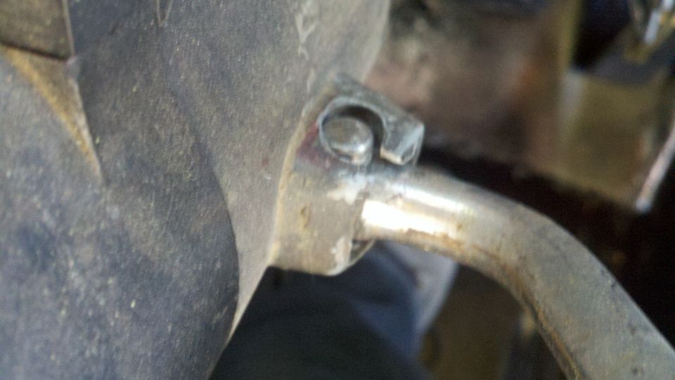 Close-up of a metal bracket attached to a pipe, with some red marks on the bracket