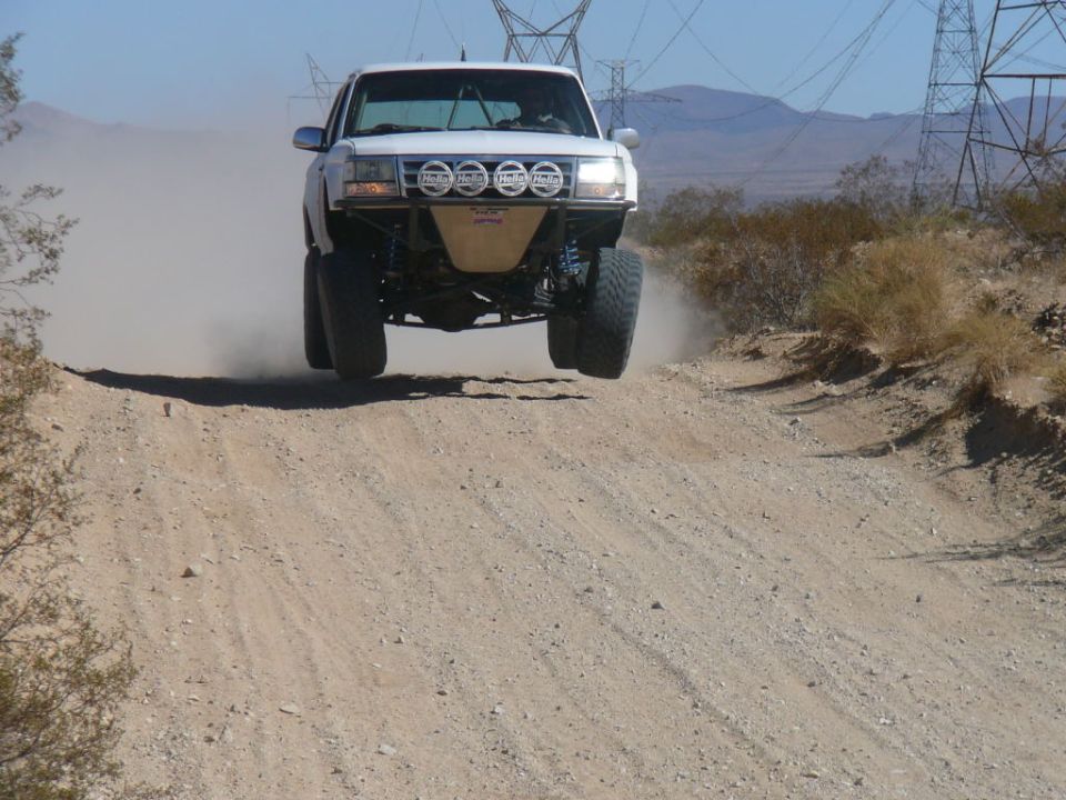 White off-road truck jumping on a dirt road, front view