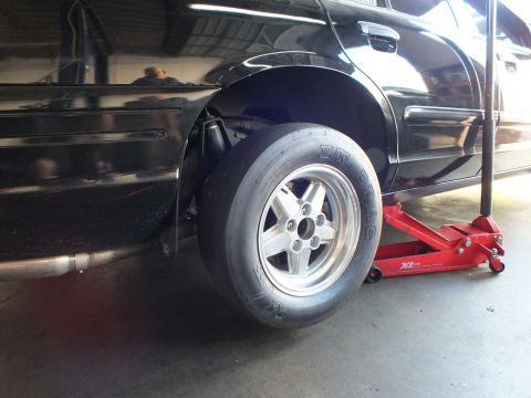 2003 Ford Crown Victoria - Side view of a black car's rear wheel fitted with an M&H ET Drag slick on a polished five-spoke wheel.