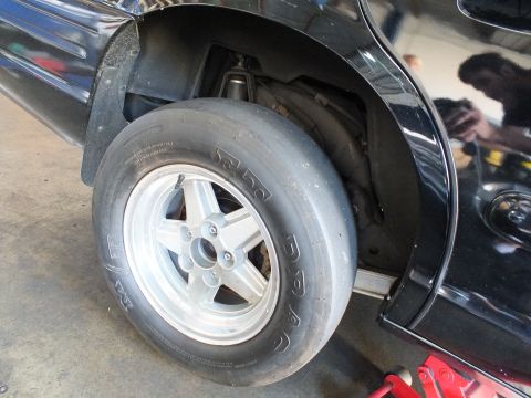 2003 Ford Crown Victoria - Rear drag wheel and slick fitted to a black sedan, with brake hardware showing inside the wheel well.