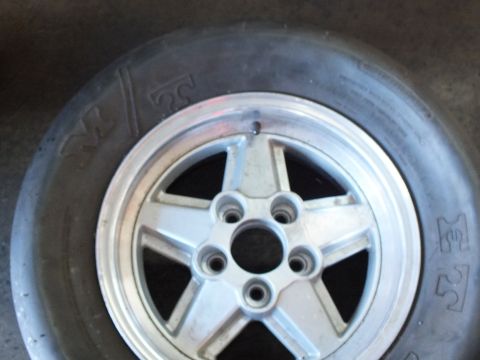 2003 Ford Crown Victoria - five-spoke aluminum wheel with a five-bolt hub sits inside a wide M&H drag slick on the shop floor.