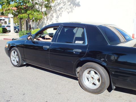 2003 Ford Crown Victoria - Profile of a blacked-out full-size sedan running a narrow front runner and a SuperMotors window decal.