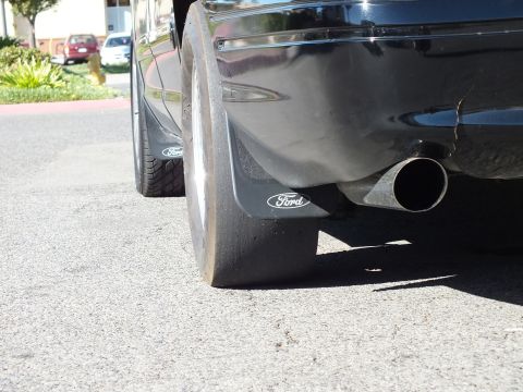 2003 Ford Crown Victoria - Rear corner detail showing Ford-logo splash guards and a polished exhaust tip.
