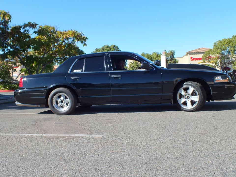 Black Ford Crown Victoria driver side profile on machined-lip wheels in parking lot