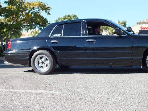 2003 Ford Crown Victoria - Side shot of a lowered black four-door, narrow front tire and SuperMotors decal.