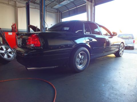 2003 Ford Crown Victoria - Lowered black four-door inside a garage, air hose coiled on the floor.