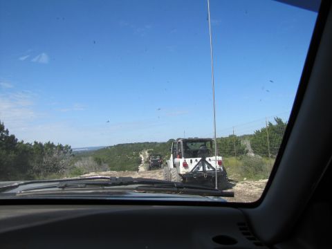 1995 Ford Bronco - A convoy of Jeeps navigates a dusty trail under a clear blue sky.