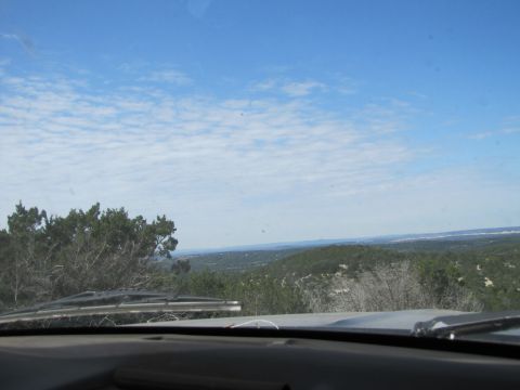 1995 Ford Bronco - View from inside a vehicle, looking out over a scenic landscape with trees and a partly cloudy sky. The Supermotors.net logo is visible on…