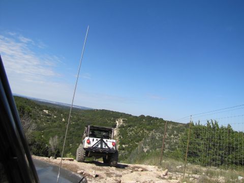 1995 Ford Bronco - White Jeep Wrangler navigates a rocky trail with a scenic overlook.