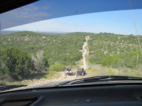 1995 Ford Bronco - View from inside a vehicle looking out at two ATVs on a trail in a rural, green landscape.