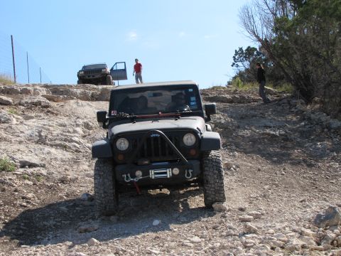 1995 Ford Bronco - Two Jeep Wranglers navigate a steep, rocky trail under a clear blue sky.