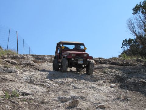1995 Ford Bronco - Jeep Wrangler navigates a challenging off-road trail on a sunny day.
