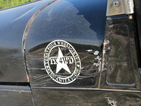 1995 Ford Bronco - Close-up of a damaged black vehicle fender a 'Texas Four Wheel Drive' sticker.