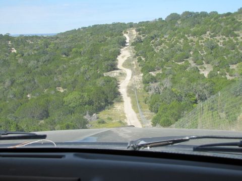 1995 Ford Bronco - Driving on a dirt road through a scenic, wooded hill country landscape.