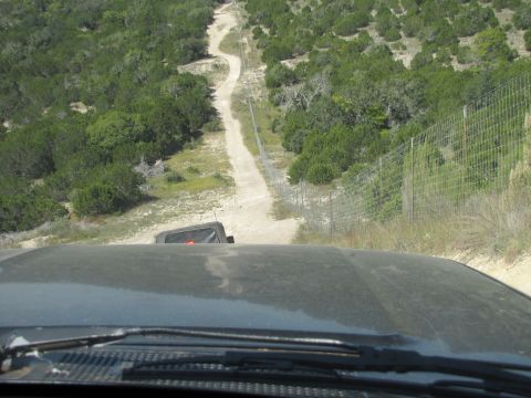 1995 Ford Bronco - Driving on a dusty dirt road through a wooded area with a fence line.