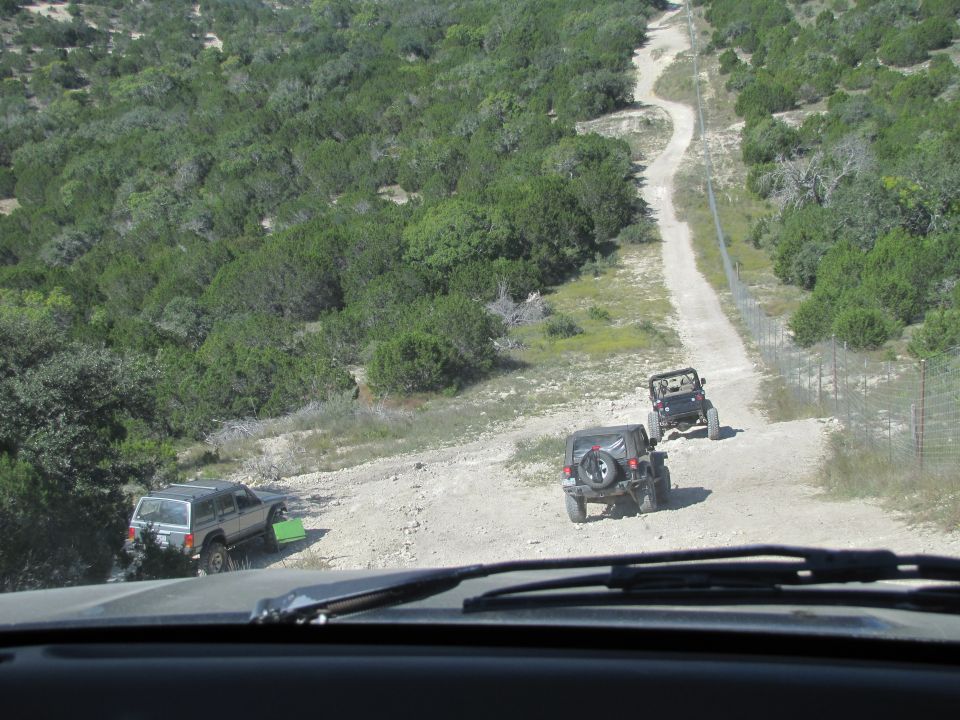 Three Jeeps driving on a dirt road through a wooded area